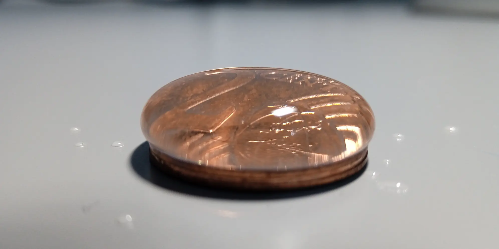 Cuentagotas echando gotas de agua sobre una moneda.