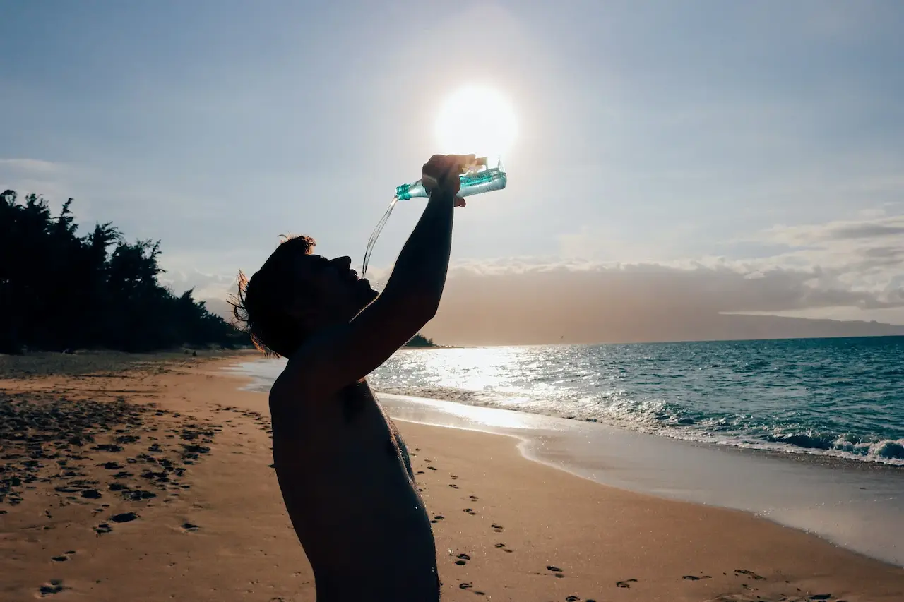 Fotografía de un hombre bebiendo agua en la playa.